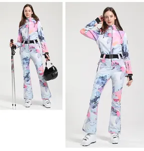 Detail view of slim fit one-piece ski suit featuring pastel watercolor print and black belt