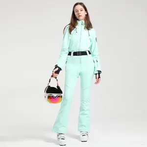 Slim fit mint green one-piece ski suit for women with windproof belt and white helmet