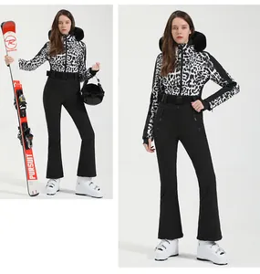 Detail of leopard print ski jacket with faux fur hood and slim black ski pants set