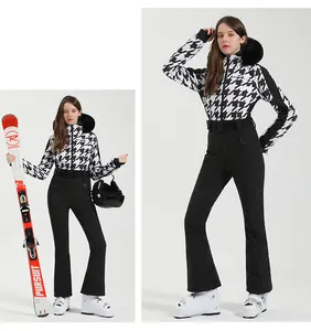 Detail of women's houndstooth ski jacket with faux fur hood and slim black pants