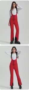 Detail of red waterproof ski bib pants with black side stripes and front zipper pockets