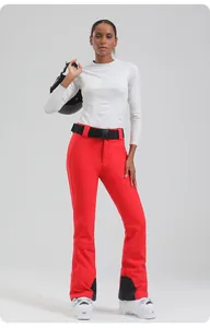 Full view of women's red slim ski pants with white thermal top and black belt detailing
