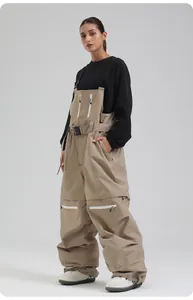 Details der khakifarbene Oversize-Skihose mit verstellbaren Trägern und weißen Reißverschlüssen