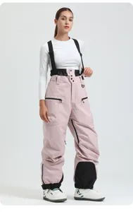 Detail view of pink bib ski pants showing high waist, black elastic belt and knee patches