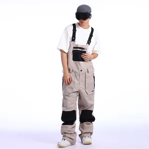 Mens waterproof beige ski bib pants with black patches and adjustable shoulder straps