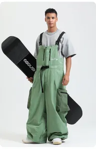 Dettaglio di spalline e tasche cargo sui pantaloni da sci impermeabili verde grigio