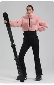 Detail of a pink faux fur ski jacket and slim fit black trousers with a professional belt
