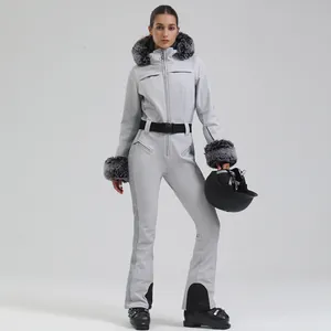 Slim fit women's one-piece ski suit in light grey with faux fur hood and black belt