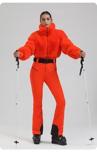 Detail of bright orange women's ski suit with faux fur jacket and slim-fit trousers