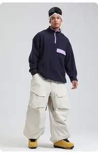 Detail of off-white loose cargo ski pants paired with a navy fleece hoodie for snow sports