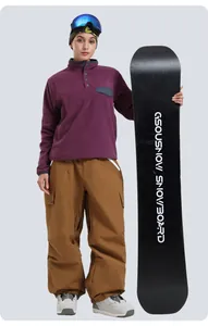 Close-up of brown baggy multi-pocket cargo ski pants paired with a GSOUSNOW snowboard