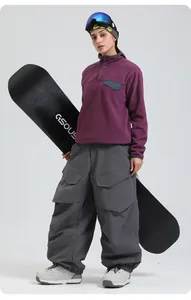 Detail of dark purple fleece top and grey multi-pocket cargo ski pants with snowboard