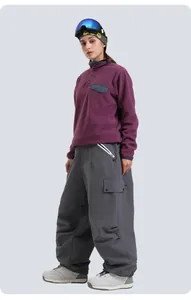 Detail of dark grey wide-leg ski pants with utility pockets and white side zippers