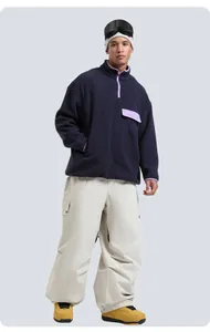 Detail of loose multi-pocket waterproof cargo ski pants paired with yellow outdoor snow boots
