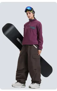 Full view of women's purple fleece top and brown cargo ski pants with a snowboard