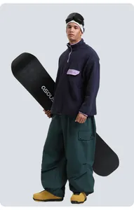 Detail view of multi-pocket ski pants with blue fleece top and GSOU snowboard