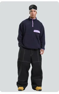 Detail of loose black snowboard pants with white contrast stitching and wide-leg design