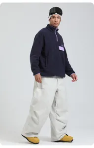 Détail du pull en polaire bleu marine avec finitions mauves et pantalon de ski large