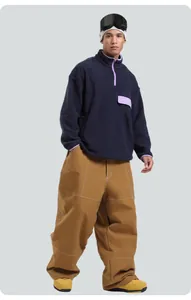 Detail view of khaki wide-leg ski pants with white stitching and navy fleece pullover