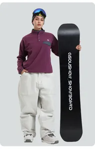 Women's ski set with purple fleece jacket, off-white loose pants and colorful goggles