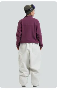Detail view of purple fleece hoodie and cream-colored wide-leg ski pants for winter sports