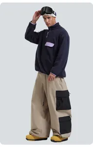 Detalle de los pantalones de esquí cargo caqui con bolsillos negros y botas de montaña