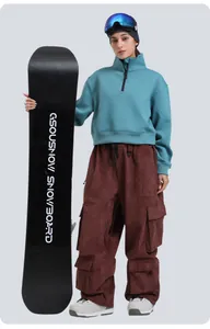 Detail of burgundy corduroy ski pants with cargo pockets and white snow boots