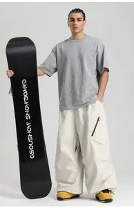 Male model wearing oversized cargo pants and outdoor boots holding a GSOUSNOW snowboard
