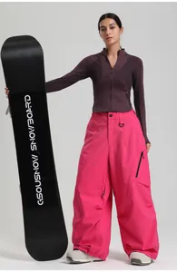 Detail of pink loose ski pants and purple zip-up base layer with a professional snowboard