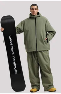 Männliches Model im armee-grünen wasserdichten Skianzug mit einem Snowboard im Studio