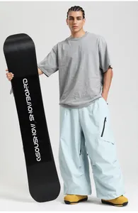 Detail view of light blue loose ski pants with black zipper pockets and snowboard