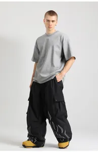 Detail of loose-fit black ski pants featuring white flame print and reflective elements