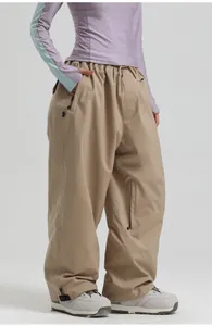 Detail view of khaki waterproof ski pants showing loose fit and side zipper pockets