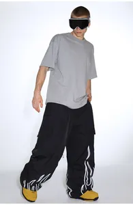 Detail of loose black cargo ski pants featuring reflective white flame print at the cuffs
