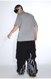 Detail of loose-fit black ski pants featuring white flame prints and cargo pockets design