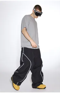 Detail view of baggy black ski pants with white streamlined piping and loose cargo fit