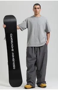 Detail view of loose-fit grey snowboard pants with yellow ski boots and a pro board