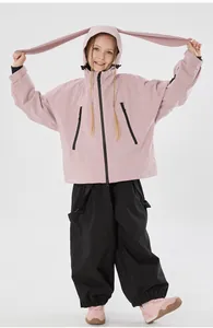 Detail of pink ski jacket with rabbit ear hood and black waterproof pants for kids