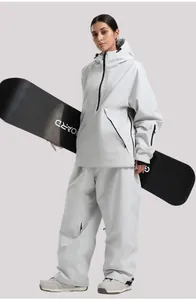 Conjunto de esquí gris claro con chaqueta con capucha y pantalón impermeable en una modelo