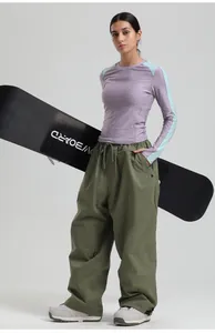 Detail of olive green wide-leg cargo ski pants paired with professional V-BOARD equipment