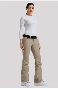 Dettaglio dei pantaloni da sci kaki slim e del top termico bianco con dettagli funzionali