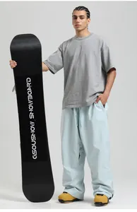 Loose fit waterproof light blue snowboard pants paired with yellow boots and a snowboard