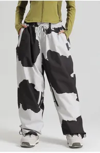 Detail of cow print ski pants featuring a wide-leg fit, drawstring waist and side zipper pocket