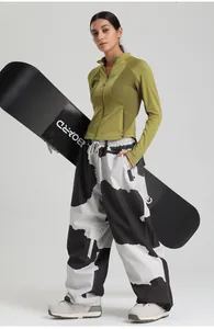 Detail of waterproof ski set featuring green zip-up jacket and black-white patterned pants
