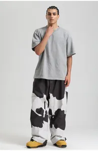Detail of loose fit cow print pants styled with gray t-shirt and yellow hiking boots