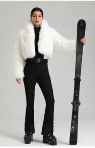 Détails d'une veste en fausse fourrure blanche et d'une combinaison de ski noire avec ceinture