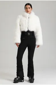 Détail d'une veste de ski blanche en fausse fourrure et d'un pantalon noir à taille haute
