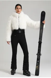 Détail de la veste de ski en fausse fourrure blanche avec un pantalon de ski noir ajusté