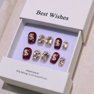 Handmade cherry red press-on nails set with glitter, dollar signs, and rhinestones in a gift box