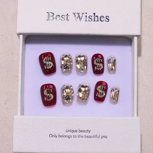 Handmade cherry red press-on nails with luxury gold dollar signs and heart crystal rhinestones